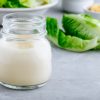 Homemade Caesar Salad Dressing in glass jar on gray stone background