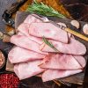 Flat slices of square sandwich ham with herbs. Dark background. Top view.