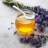 Jar with honey and fresh lavender flowers on a concrete background
