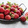 Fresh ripe delicious strawberries in a metal bowl on a gray stone background
